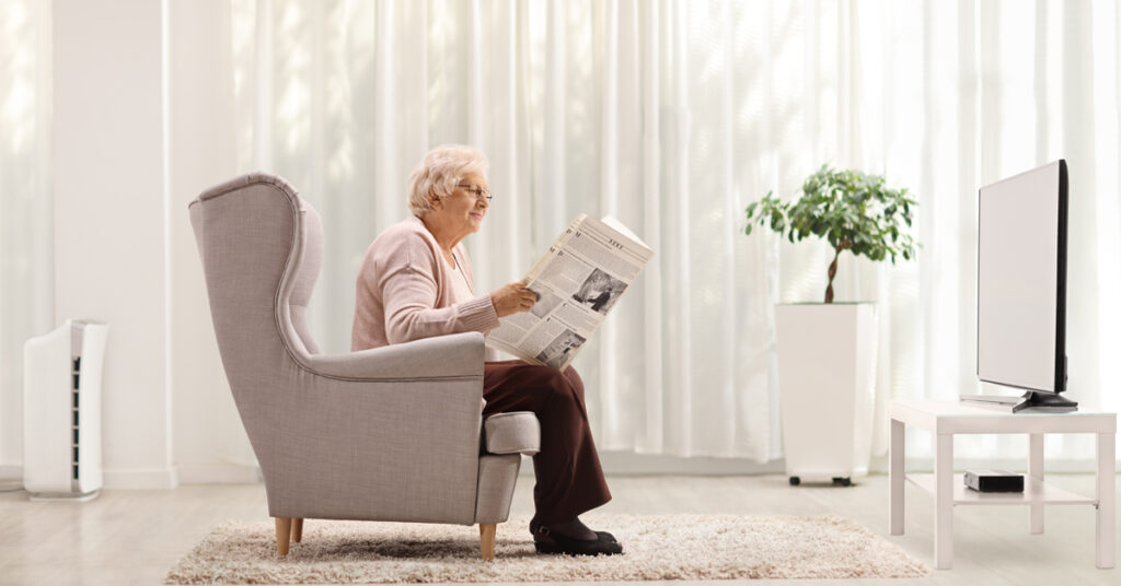 Eine Pensionärin, Oma, Großmutter in einem Ohrensessel, Die Zeitung lesend